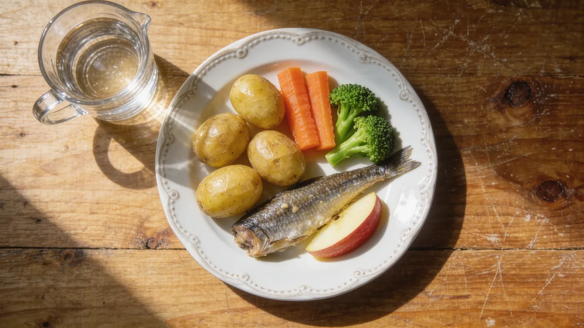 Symbolbild: Teller mit Kartoffeln, Gemüse und Fisch auf einem Küchentisch von oben